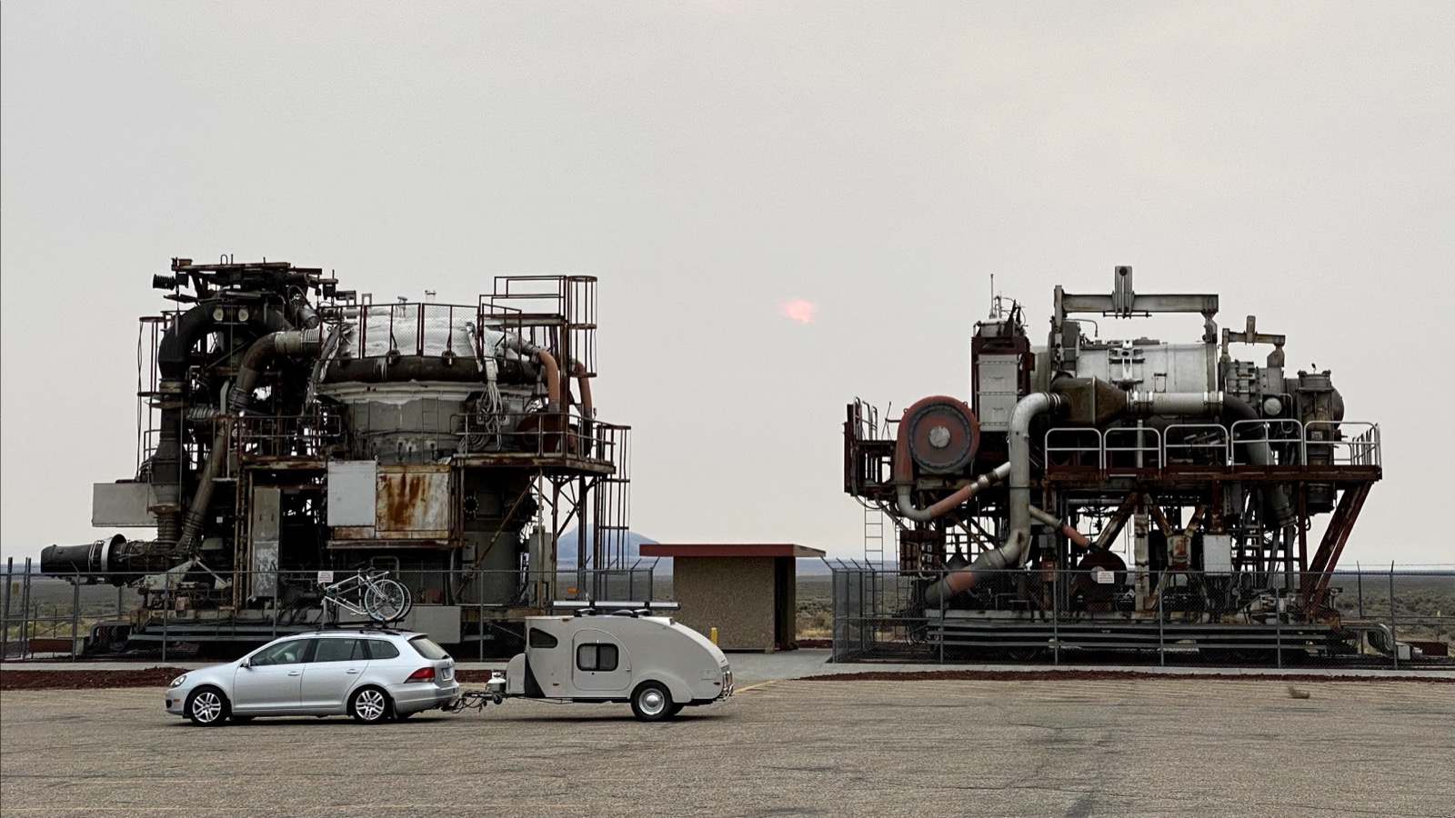 Car and camper trailer at dusk with industrial structures
