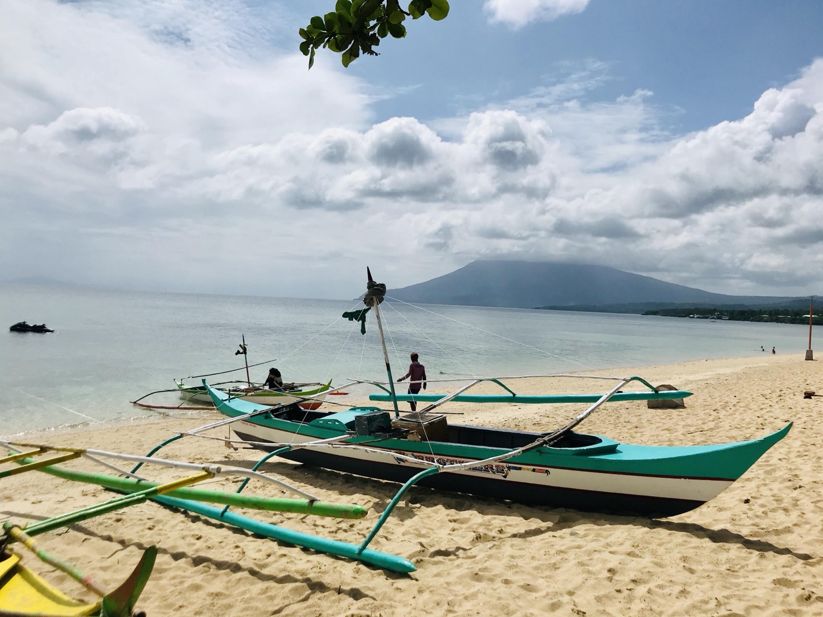 Tropical coastline with outrigger boats and a volcano in the background
